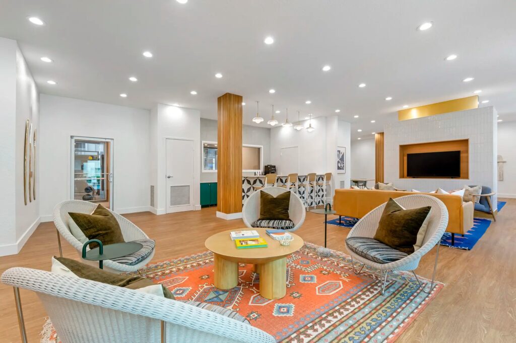 Clubhouse sitting area with chairs, couches, and access to the kitchen area in the back