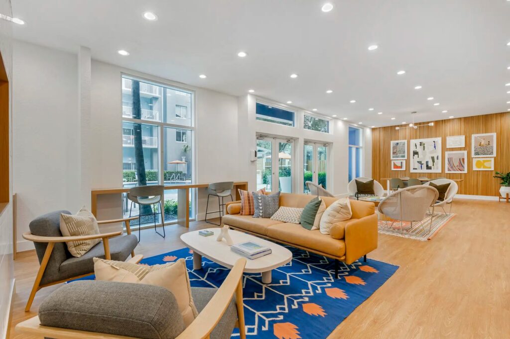 Clubhouse sitting area with couch and chairs with window looking out to pool area