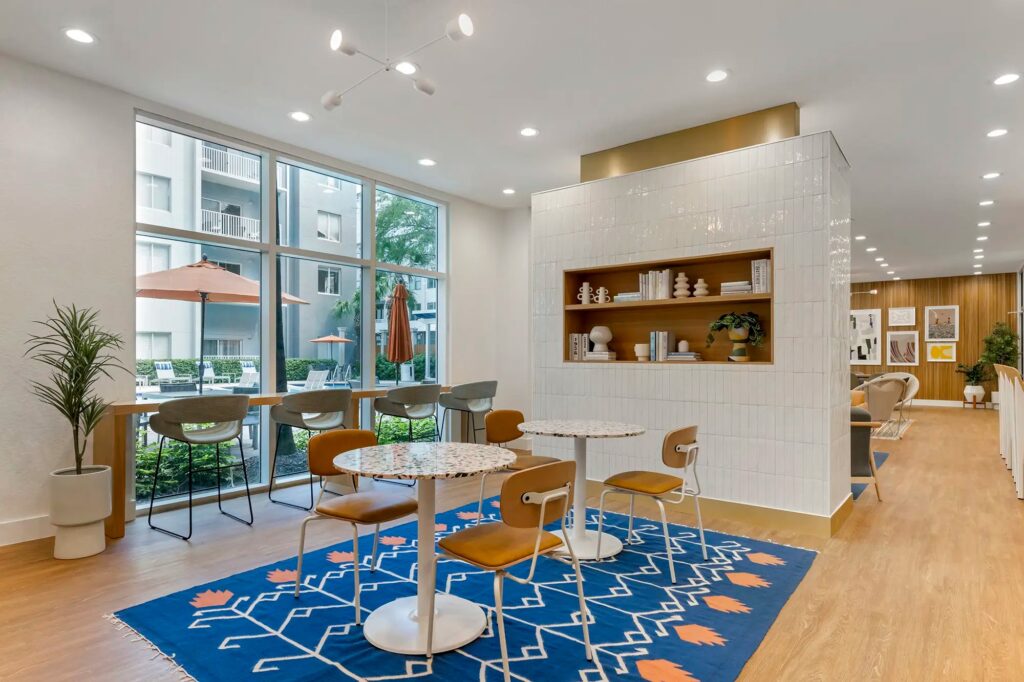 Clubhouse area with tables and chairs and windows looking out to pool area