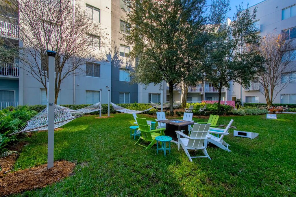 Courtyard with lots of grass, lawn chairs with fire pit, and hammocks