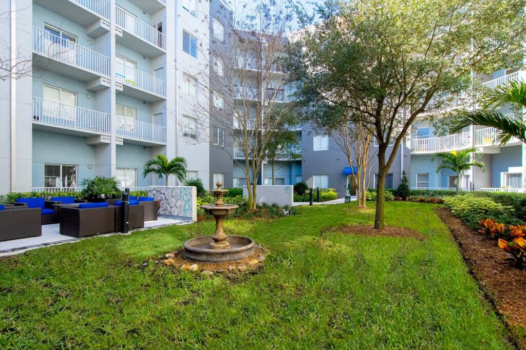 Courtyard with lots of grass and spaced out seating areas. Fountain in the middle of the grass