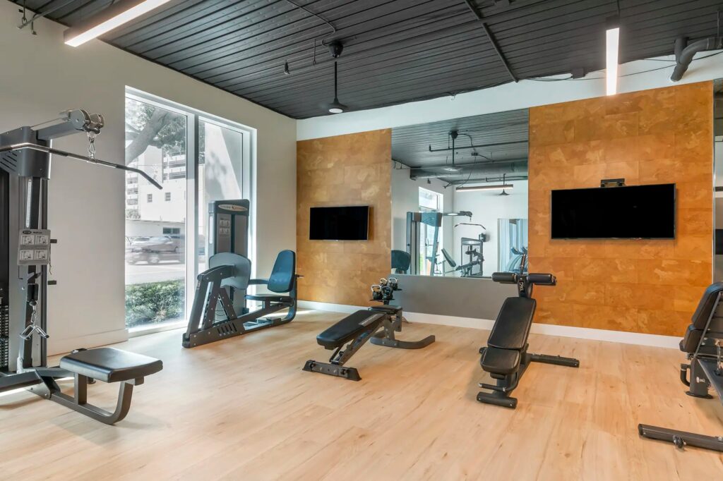 Fitness center with strength training eqipment and tvs mounted on the wall