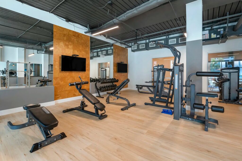 fitness center with strength training equipment, mirrors, and tvs mounted on the walls