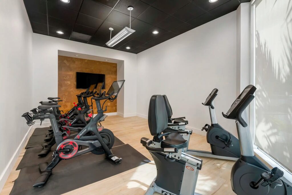 fitness center with cardio equipment and peleton bikes with tv mounted on wall