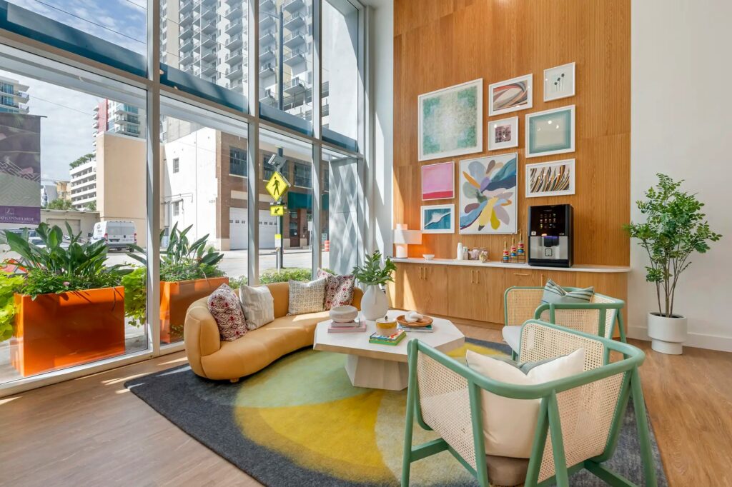 Leasing office waiting area with couch and chairs and coffee maker and street view
