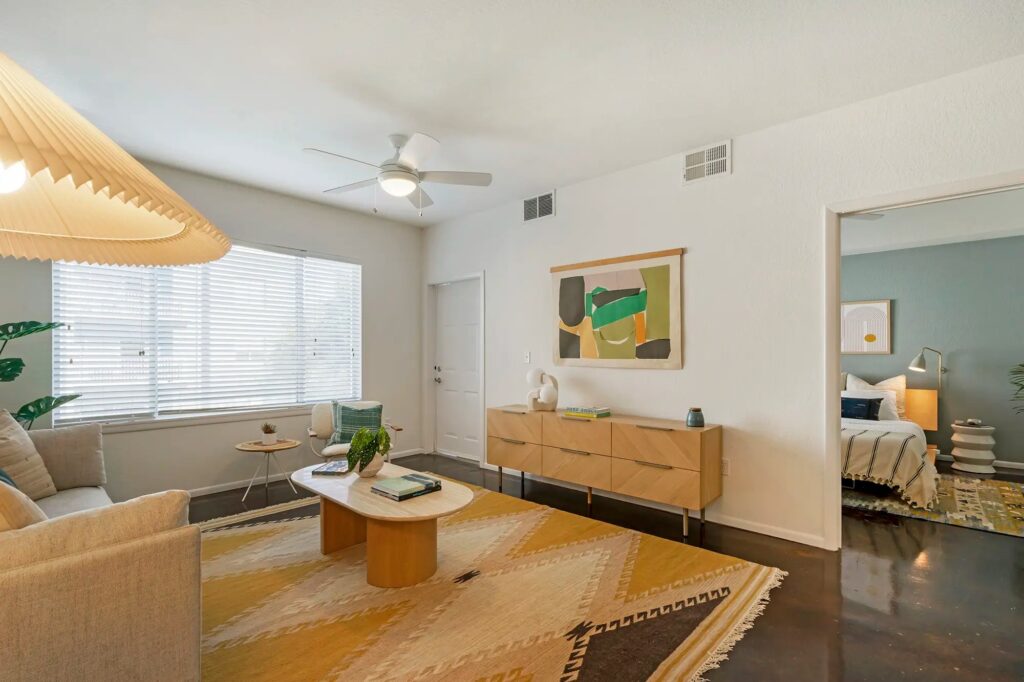 Living room with large window and cement floors with access to front door with view of bedroom