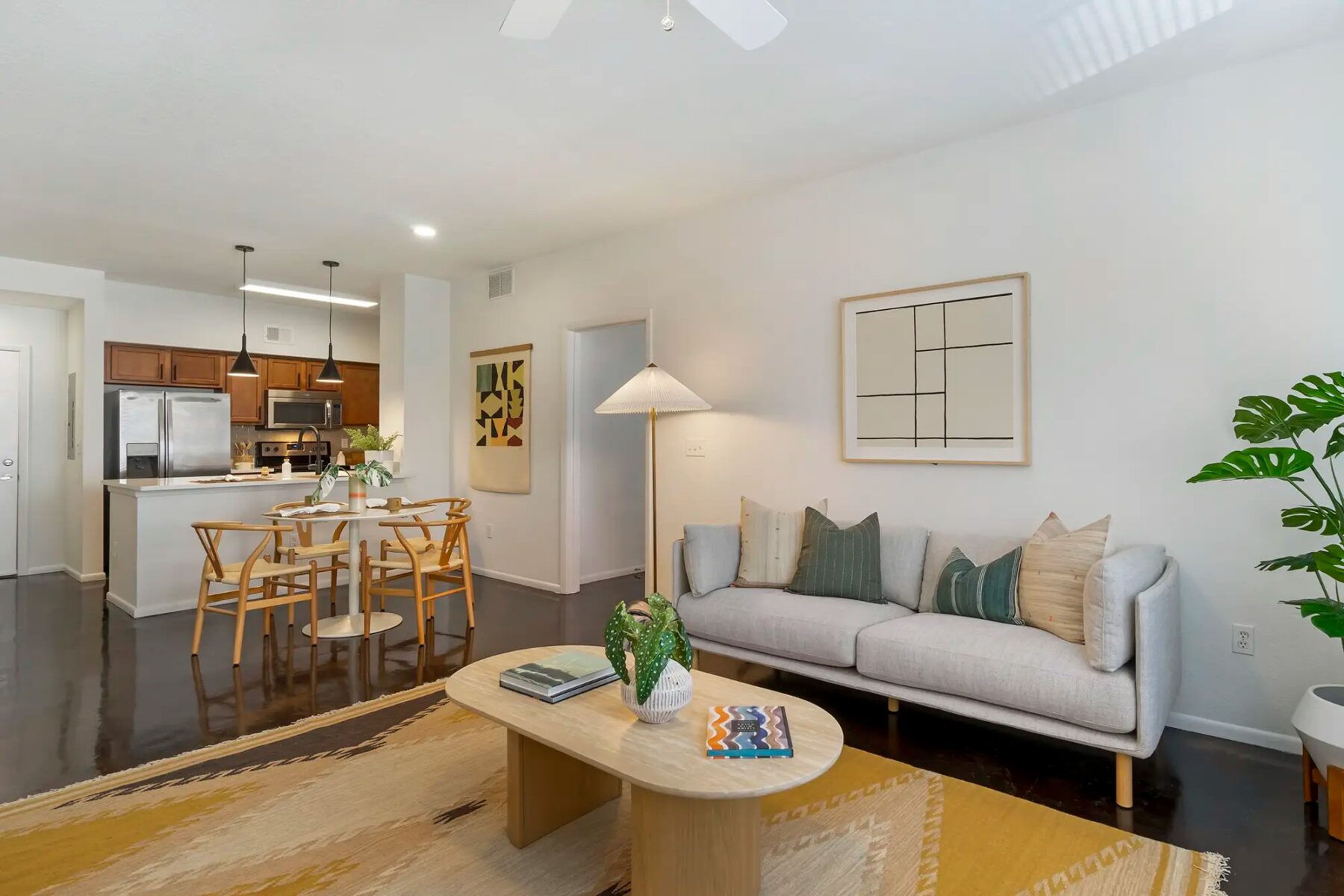 living room with cement floors, ceiling fan, with view of dining room and kitchen with stainless steel appliances