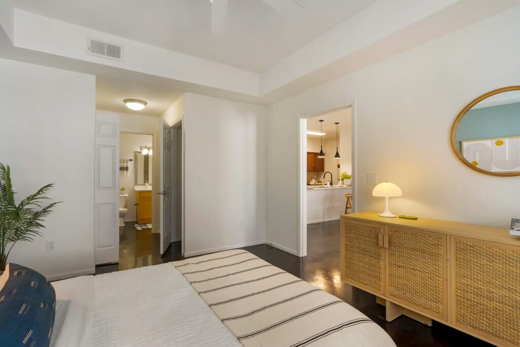 Bedroom with cement floors and ceiling fan with access to bathroom and kitchen