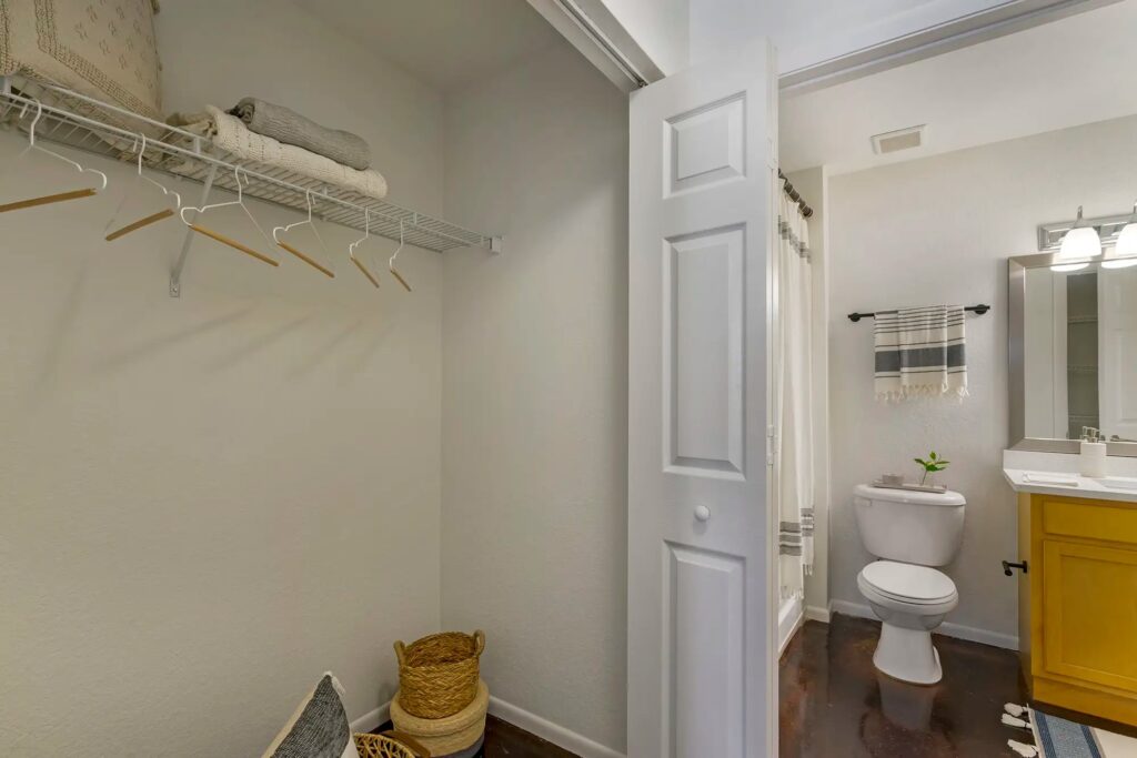 Closet area in bedroom with built in shelf and access to the bathroom with updated fixtures