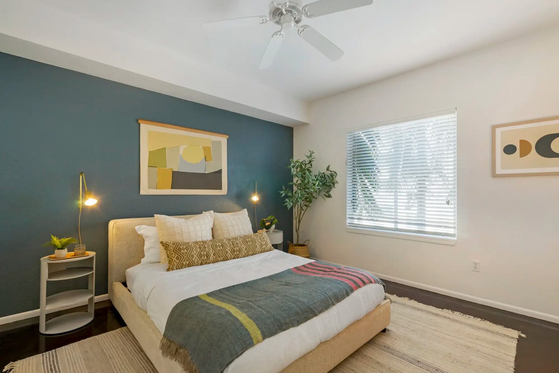 Bedroom with cement floors, large window, accent wall, and ceiling fan